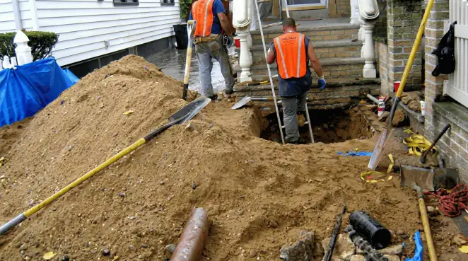Contractors performing foundation protection and exterior drainage excavation near residential home steps in Boston, MA